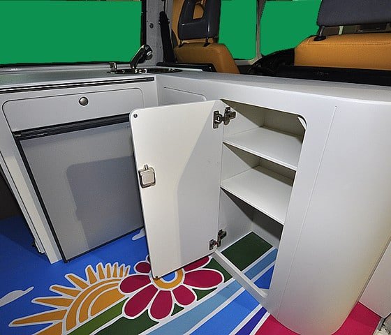 Suelo con vinilo decorativo de flores de colores y mueble blanco con la puerta abierta en una furgoneta camper